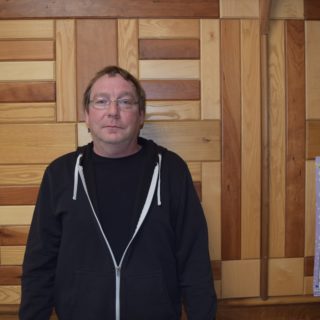 Headshot of Richard Pace standing in front of a wooden wall.