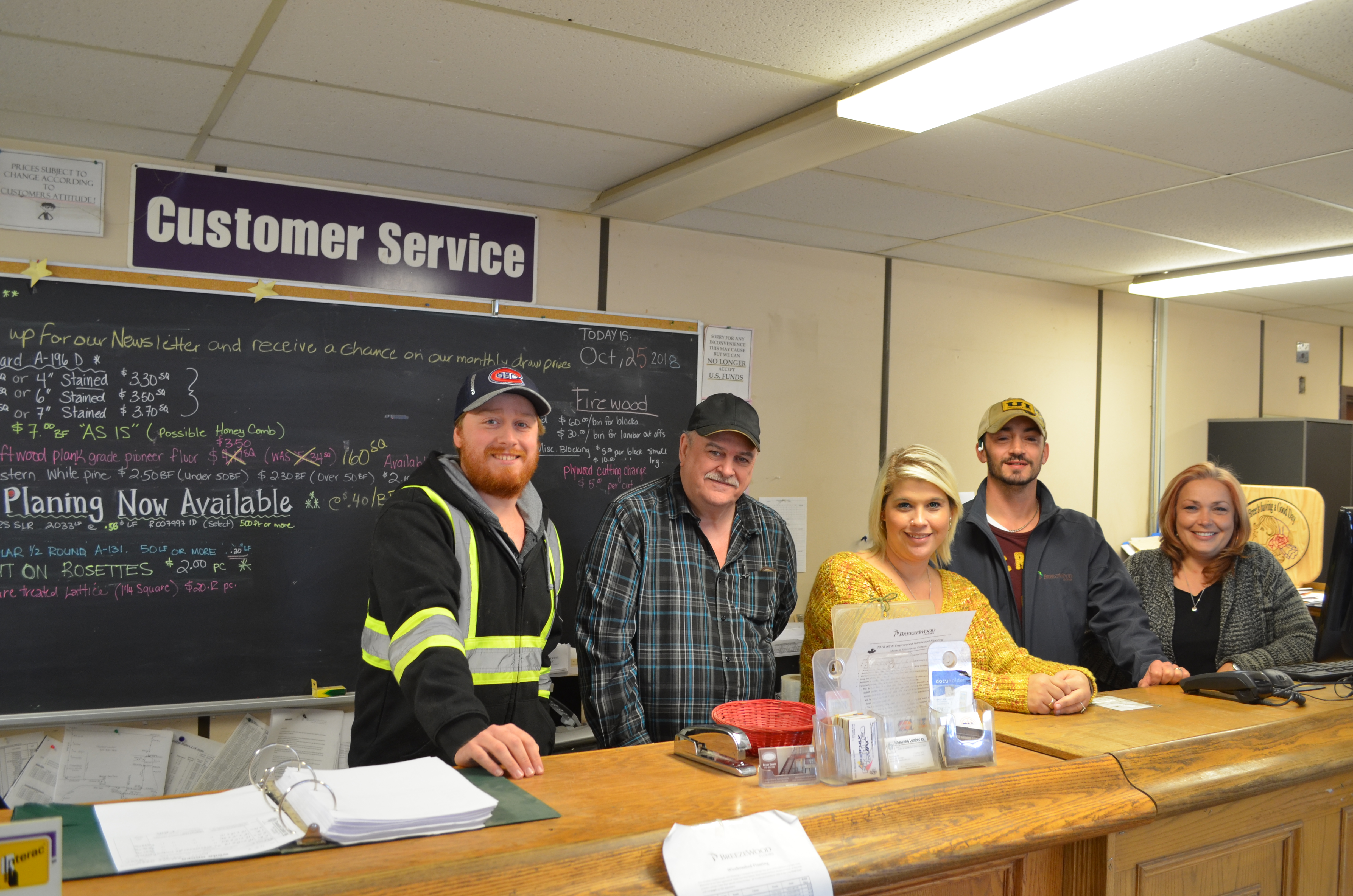 Three men and two women are standing indoors at the Retail Lumber Shop.