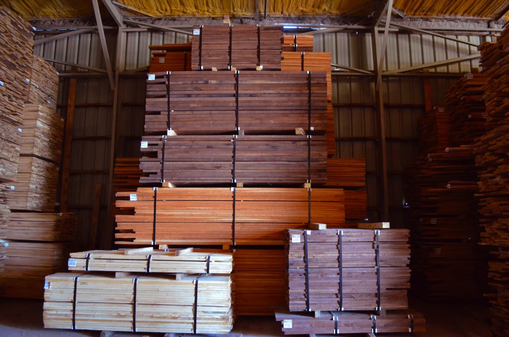 Dark wood panels stacked in concrete wearhouse.