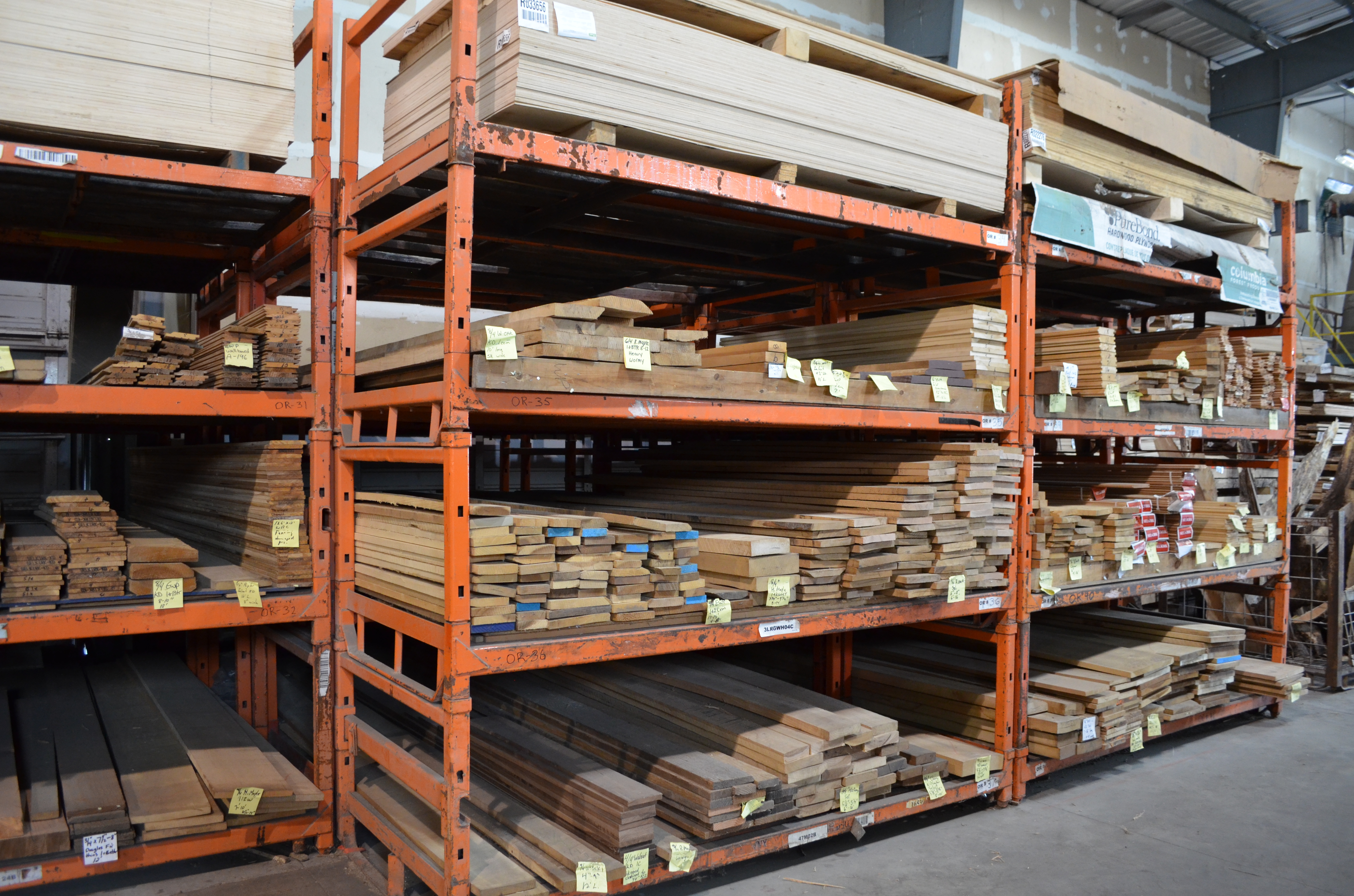 planks of wood organized by size and colour with yellow tags on the end. The wood is filled into cubbys.