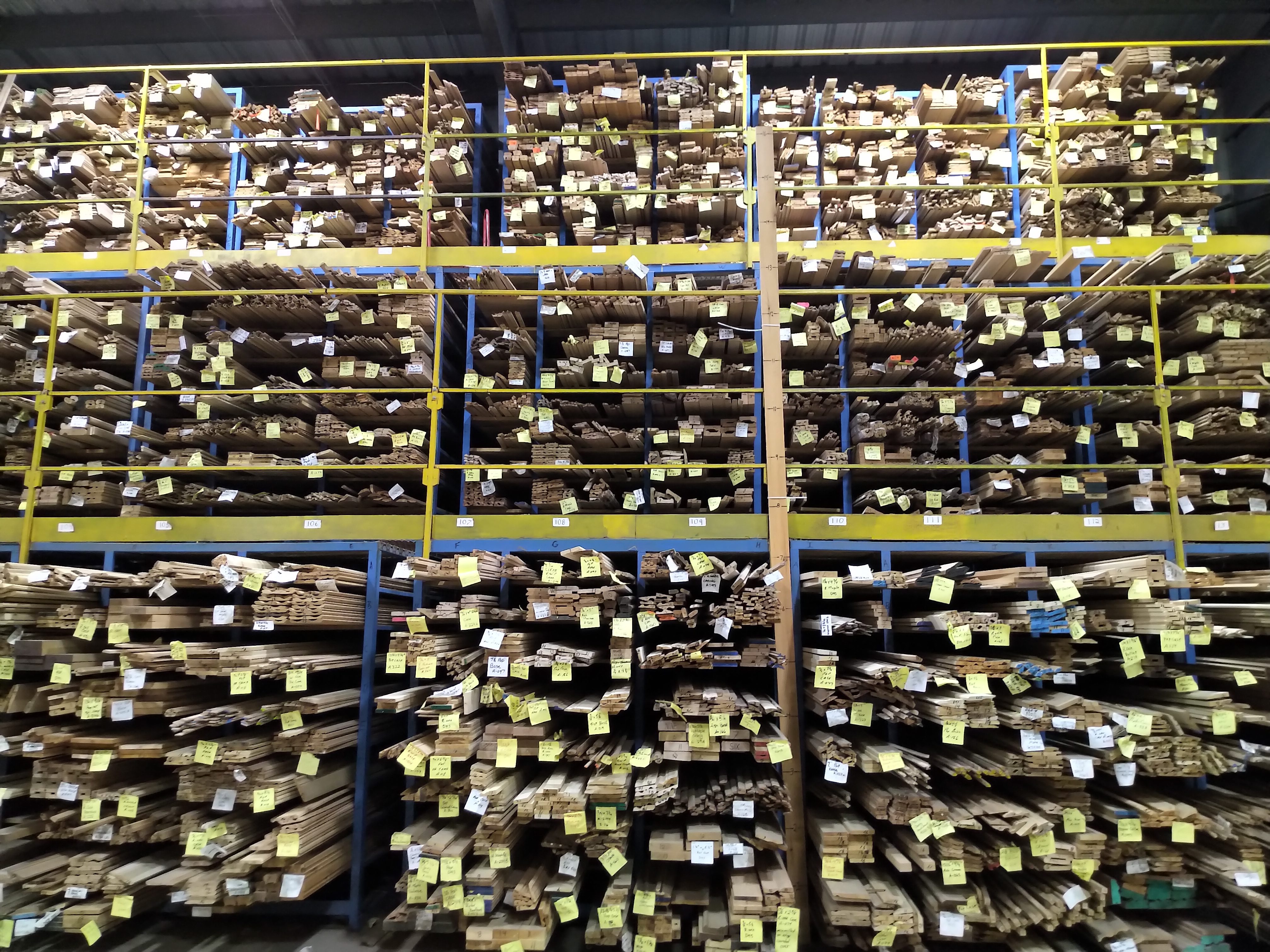 planks of wood organized by size and colour with yellow tags on the end. The wood is filled into cubbys.