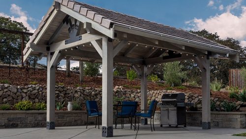 outdoor-accents-avant-section_party pavilion Pavillion with party lights covering a table and chairs set with a bbq. Photo taken on a sunny day.